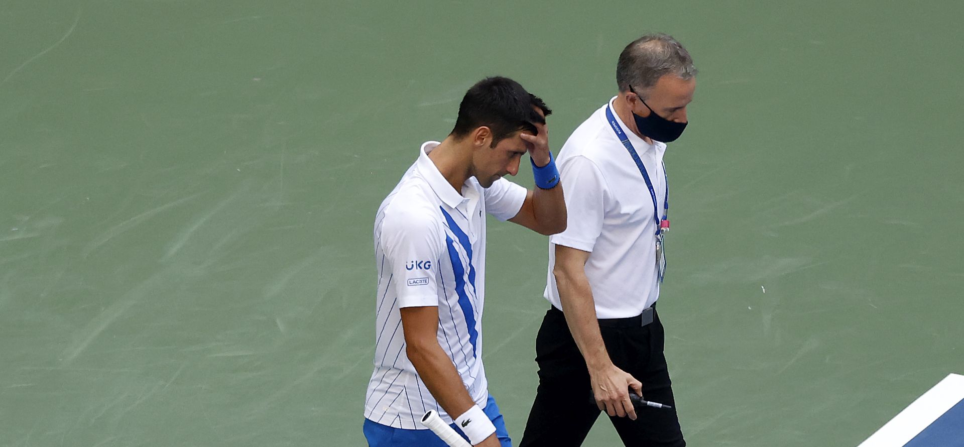 epa08651673 Novak Djokovic of Serbia (L) as walks off the court with the Head of Officiating at International Tennis Federation (ITF) Soeren Friemel after he accidentally hit a linesperson with a ball in the throat during his match against Pablo Carreno Busta of Spain on the seventh day of the US Open Tennis Championships at the USTA National Tennis Center in Flushing Meadows, New York, USA, 06 September 2020. Djokovic was defaulted from tournament. Due to the coronavirus pandemic, the US Open is being played without fans and runs from 31 August through 13 September.  EPA/JASON SZENES