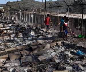 epa08656942 Asylum seekers walk among debris in the Moria refugees camp on the island of Lesbos, Greece, 09 September 2020. According to reports, a fire broke out at Moria Camp early on 09 September, after approximately 35 refugees, who had tested positive for COVID-19, refused to move into isolation with their families.  EPA/ORESTIS PANAGIOTOU