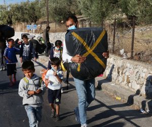 epa08658104 Asylum seekers evacuate from Moria refugee camp after a fire that broke out in the camp, Greece, 10 September 2020. A passenger ferry and two Navy landing ships will accommodate about 2,000 refugees who are homeless after the fire at Moria, Migration and Asylum Minister Notis Mitarachi said. The island of Lesvos was declared in state of emergency for four months, by order of Deputy Civil Protection and Management Crises Minister Nikos Hardalias and the general secretary of civil protection Vassilis Papageorgiou.  EPA/ORESTIS PANAGIOTOU