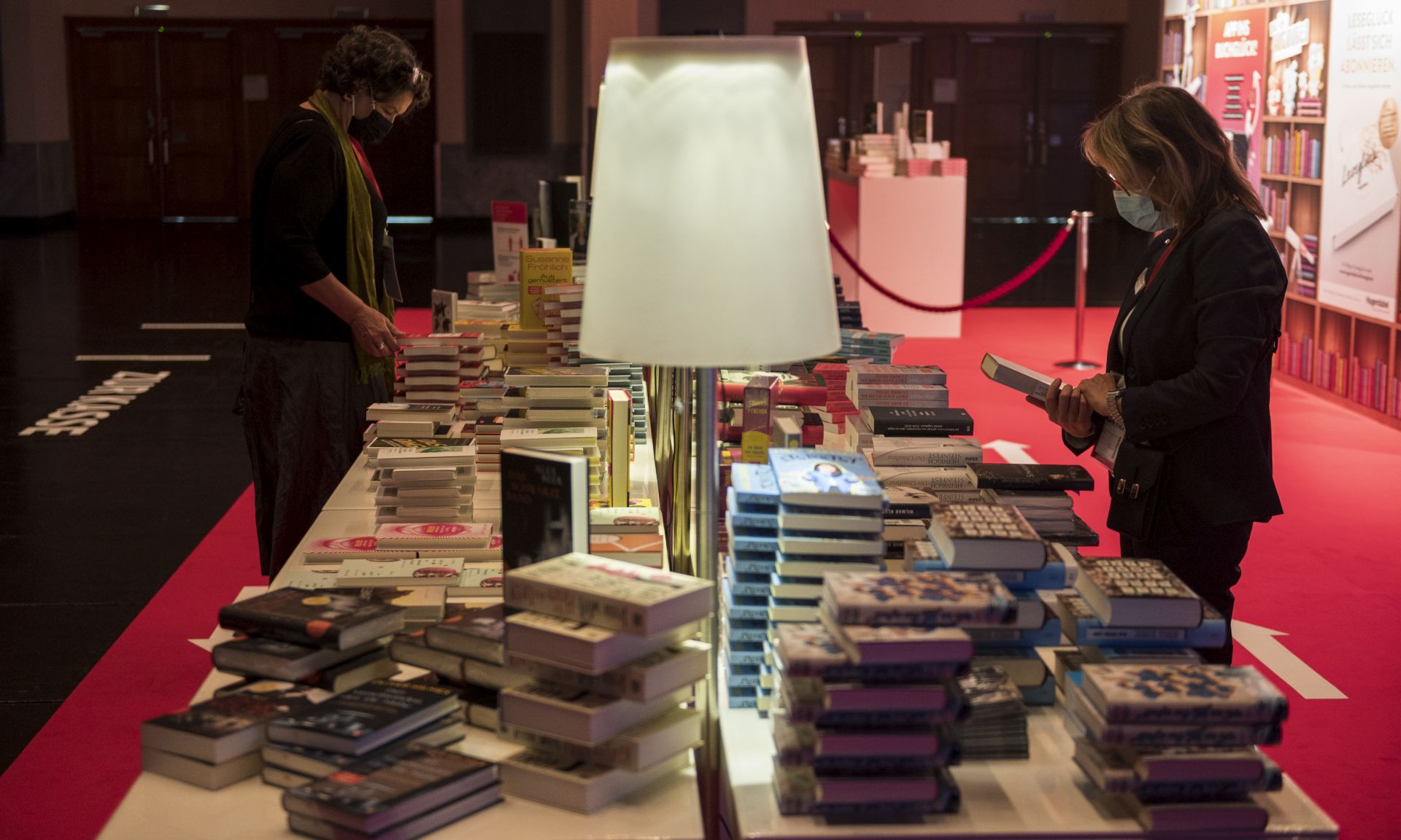 epa08741677 Women look at some books before the opening of the 2020 Frankfurt Book Fair amid the coronavirus pandemic in Frankfurt am Main, Germany, 13 October 2020. The Frankfurt Book Fair is the world's largest trade fair for books and is taking place this year at a smaller scale and with many events either online or scattered throughout the city of Frankfurt due to the pandemic. Canada is this year's guest country.  EPA/THOMAS LOHNES / POOL