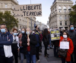 epa08755251 A person (R) holds the controversial cover of the Charlie Hebdo satirical weekly showing the caricatures of the Prophet Mohammed as people gather at the Place de la Republique for a demonstration against terrorism and to pay their respect after French teacher Samuel Paty was beheaded, in Paris, France, 18 October 2020. On 16 October French school teacher Samuel Paty was decapitated by 18-year-old attacker named Abdoulakh Anzorov who has been shot dead by policemen. Paty was a history teacher who had recently shown caricatures of the Prophet Mohammed in class.  EPA/YOAN VALAT