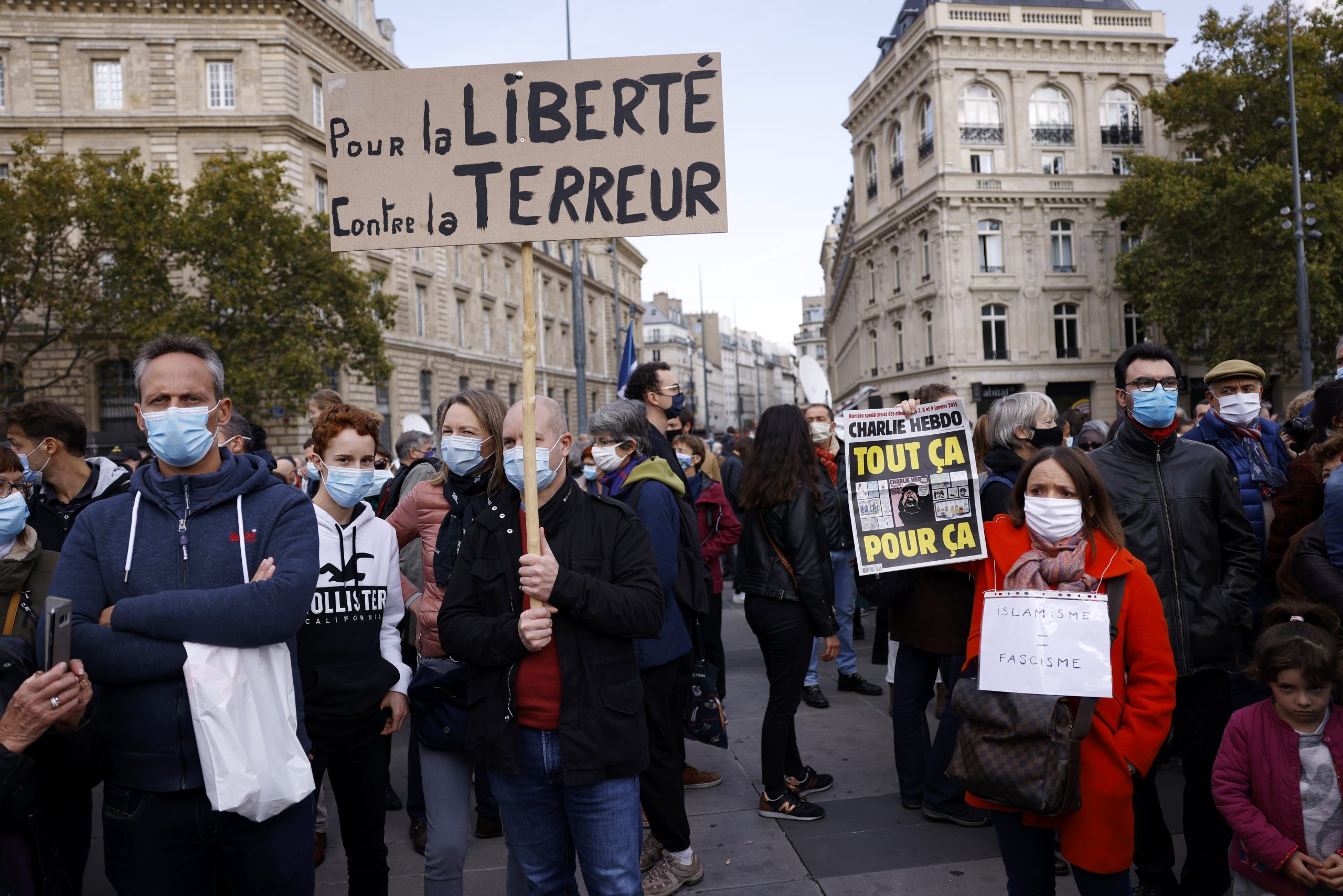 epa08755251 A person (R) holds the controversial cover of the Charlie Hebdo satirical weekly showing the caricatures of the Prophet Mohammed as people gather at the Place de la Republique for a demonstration against terrorism and to pay their respect after French teacher Samuel Paty was beheaded, in Paris, France, 18 October 2020. On 16 October French school teacher Samuel Paty was decapitated by 18-year-old attacker named Abdoulakh Anzorov who has been shot dead by policemen. Paty was a history teacher who had recently shown caricatures of the Prophet Mohammed in class.  EPA/YOAN VALAT