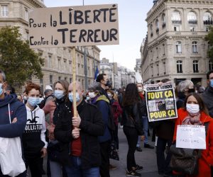 epa08755251 A person (R) holds the controversial cover of the Charlie Hebdo satirical weekly showing the caricatures of the Prophet Mohammed as people gather at the Place de la Republique for a demonstration against terrorism and to pay their respect after French teacher Samuel Paty was beheaded, in Paris, France, 18 October 2020. On 16 October French school teacher Samuel Paty was decapitated by 18-year-old attacker named Abdoulakh Anzorov who has been shot dead by policemen. Paty was a history teacher who had recently shown caricatures of the Prophet Mohammed in class.  EPA/YOAN VALAT