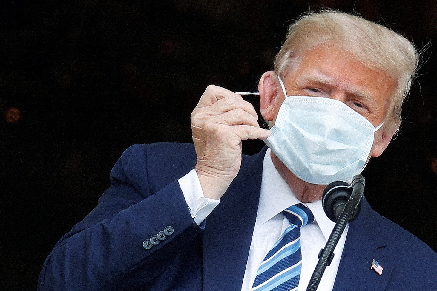 U.S. President Donald Trump holds a campaign rally on the South Lawn of the White House in Washington U.S. President Donald Trump takes off his face mask as he comes out on a White House balcony to speak to supporters gathered on the South Lawn for a campaign rally that the White House is calling a "peaceful protest" in Washington, U.S., October 10, 2020. REUTERS/Tom Brenner TOM BRENNER