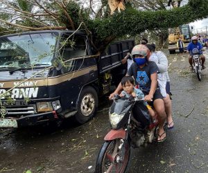 epa08790236 Filipino villagers maneuver under a toppled tree in the typhoon-hit town of Tigaon, Camarines Sur, Philippines, 01 November 2020. Super Typhoon Goni, with winds forecasted to reach 249 kilometers per hour, made landfall in the provinces of Albay and Camarines sur, according to the local weather bureau.  EPA/FRANCIS R. MALASIG