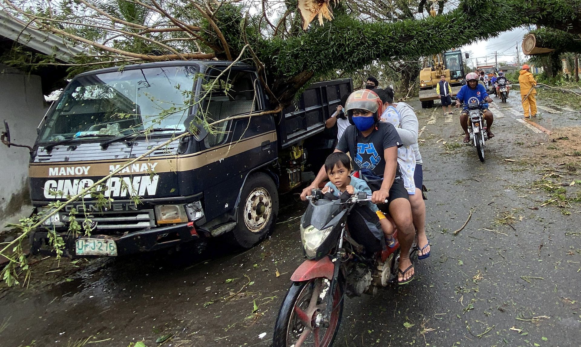 epa08790236 Filipino villagers maneuver under a toppled tree in the typhoon-hit town of Tigaon, Camarines Sur, Philippines, 01 November 2020. Super Typhoon Goni, with winds forecasted to reach 249 kilometers per hour, made landfall in the provinces of Albay and Camarines sur, according to the local weather bureau.  EPA/FRANCIS R. MALASIG