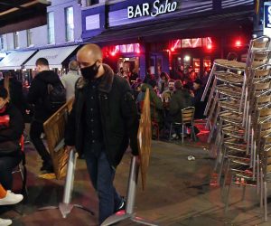 epa08799516 A bar staffer packs away tables and chairs at a bar in Soho before lockdown in London, Britain, 04 November 2020. The UK government have announced that the UK will begin its second national lockdown from 05 November. This comes as news reports state that COVID-19 related deaths in Britain have increased by 46 percent in less than a week.  EPA/ANDY RAIN