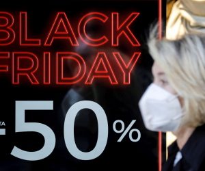 epa08825345 A woman walks past a shop advertising Black Friday sales in Valencia, Spain, 17 November 2020. Black Friday, imported to Spain from the USA, will be held next 27 November 2020, although some shops will be starting on previous days to encourage sales as the coronavirus pandemic is still affecting their businesses.  EPA/Ana Escobar