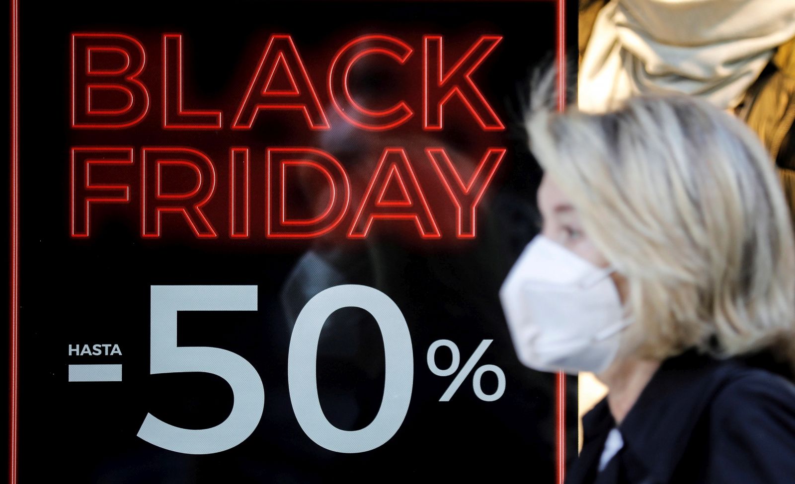 epa08825345 A woman walks past a shop advertising Black Friday sales in Valencia, Spain, 17 November 2020. Black Friday, imported to Spain from the USA, will be held next 27 November 2020, although some shops will be starting on previous days to encourage sales as the coronavirus pandemic is still affecting their businesses.  EPA/Ana Escobar