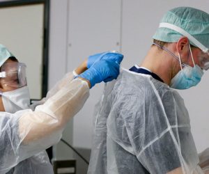 epa08827336 Nurse from Belgian Defense get prepared with protective clothes while a first patient with COVID-19 is transferred from a hospital to the Cliniques de l'Europe, Saint-Michel site following the opening of a COVID-19 hospitalization unit managed by Defense in Brussels, Belgium, 18 November 2020.  EPA/STEPHANIE LECOCQ