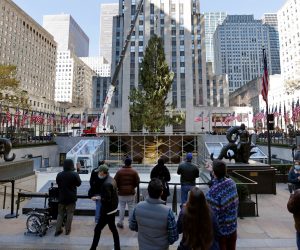 epa08820413 Spectators watch the Rockefeller Center Christmas tree guided into place in Rockefeller Center Plaza in New York, New York, USA, 14 November 2020. The 75-foot tall Norway Spruce tree will be lit up for the holiday season next month.  EPA/PETER FOLEY