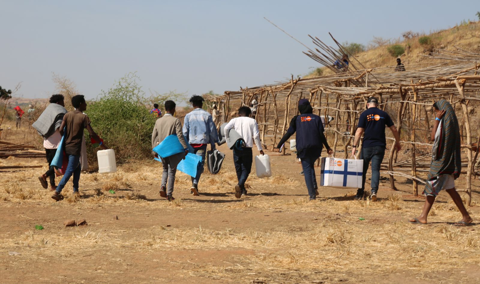 epa08845188 A handout photo made available by the United Nations Population Fund (UNFPA) showing people carrying supplies in Um Raquba camp, Sudan, 18 November 2020 (Issued 26 November 2020). Sudan received some 27,000 refugees escaping the violence in the Tigray region in northern Ethiopia.  EPA/Sufian Abdul-Mouty / UNFPA HANDOUT  HANDOUT EDITORIAL USE ONLY/NO SALES