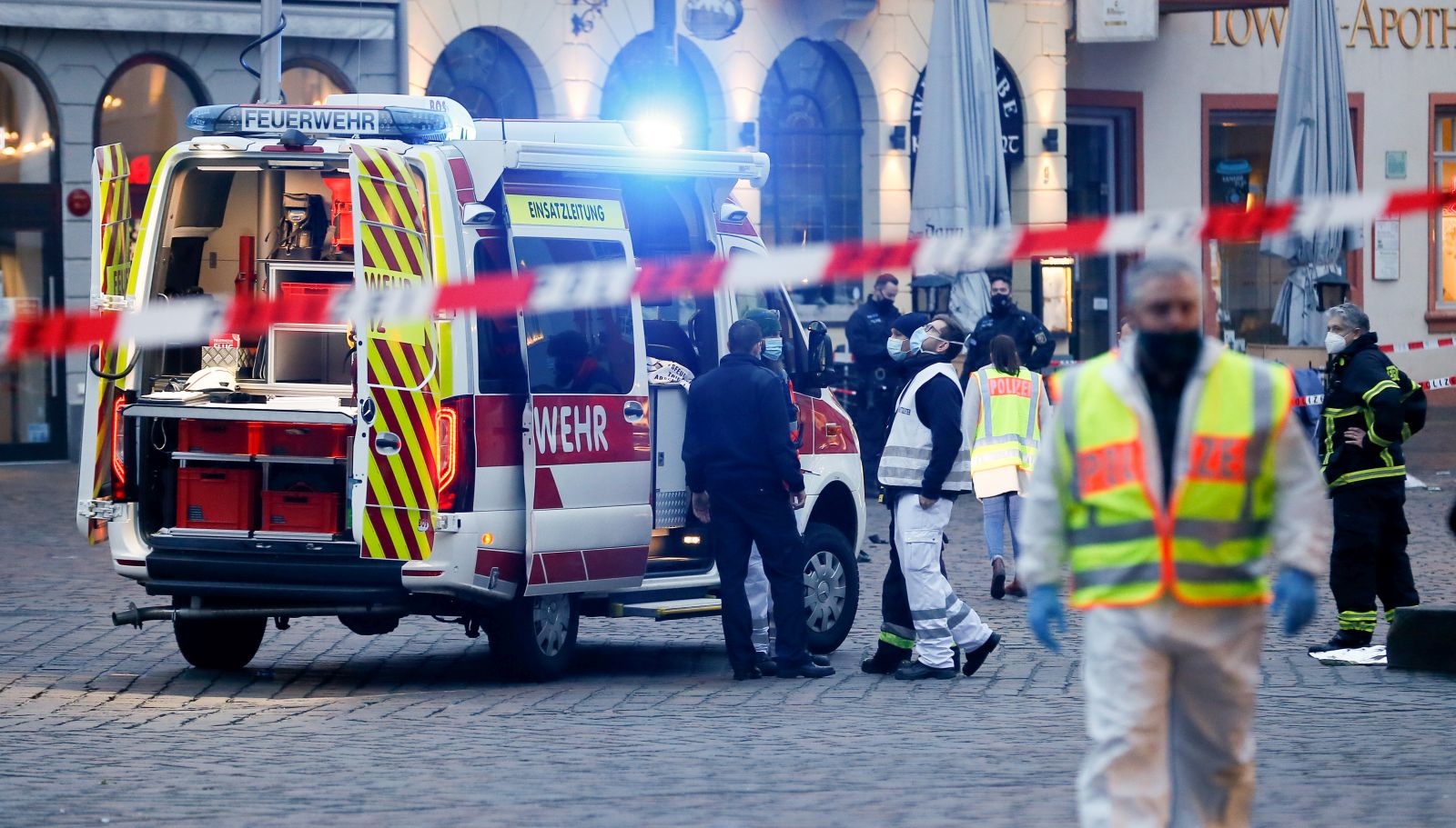 epa08855063 Policemen and a firefighting vehicle behind warning tape in a pedestrian zone in the city center in Trier, Germany, 01 December 2020.  According to reports, at least two people have been killed and several injured after a car with high speed hit into pedestrians in the inner city of Trier. Police arrested the  driver and the car was seized.  EPA/JULIEN WARNAND