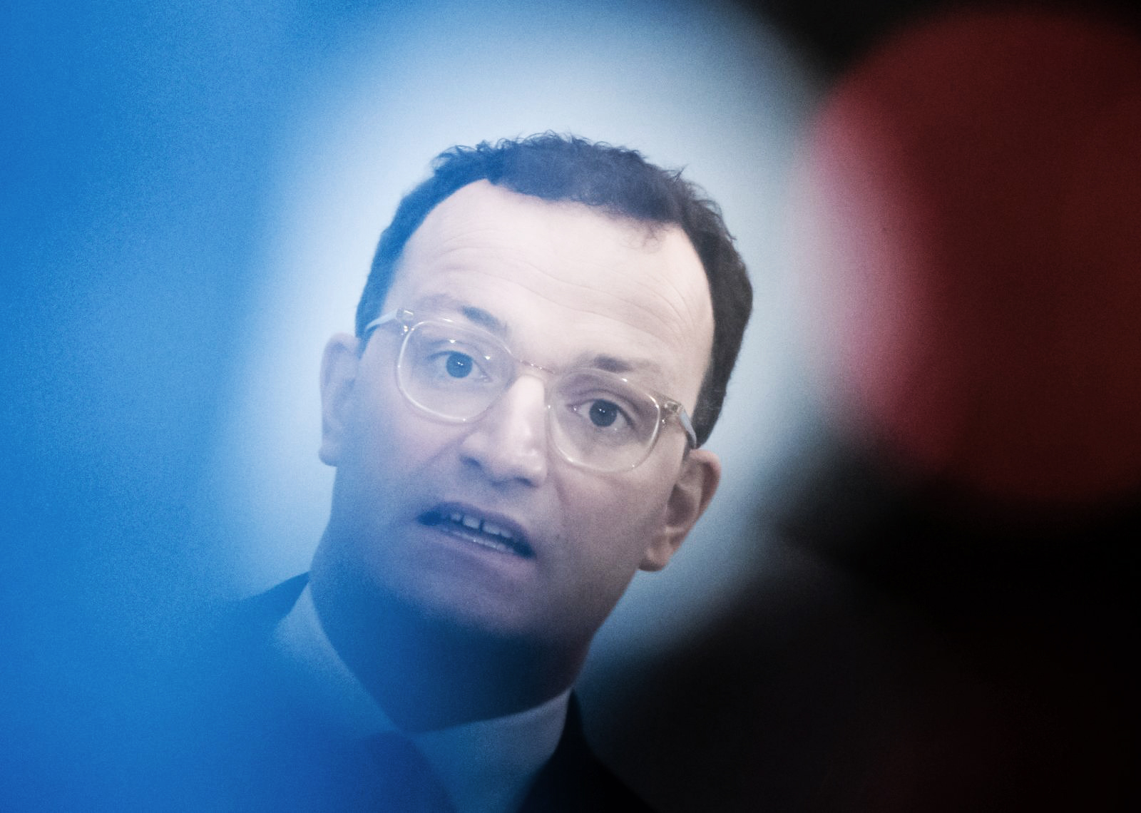 epa08862094 German Health Minister Jens Spahn is seen behind reflecting lights of a TV camera during a press statement in Berlin, Germany, 04 December 2020. German Health Minister Jens Spahn and Federal Government Commissioner for Nursing Andreas Westerfellhaus presented on 04 December 2020 a guideline as an assistance in the development of visit concepts for nursing homes.  EPA/CLEMENS BILAN