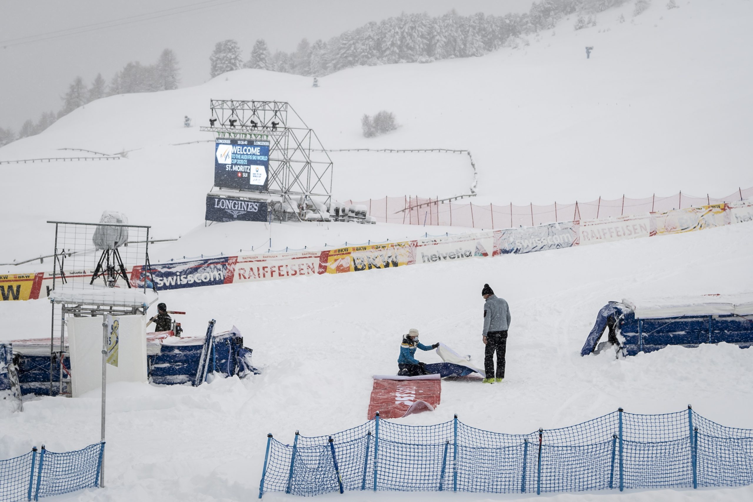epa08863368 Volunteers work in the finish area, in St. Moritz, Switzerland, 05 December 2020. Due to a heavy snowfall and strong wind, the FIS decided to cancel the women's Super-G race of the FIS Alpine Ski World Cup.  EPA/JEAN-CHRISTOPHE BOTT