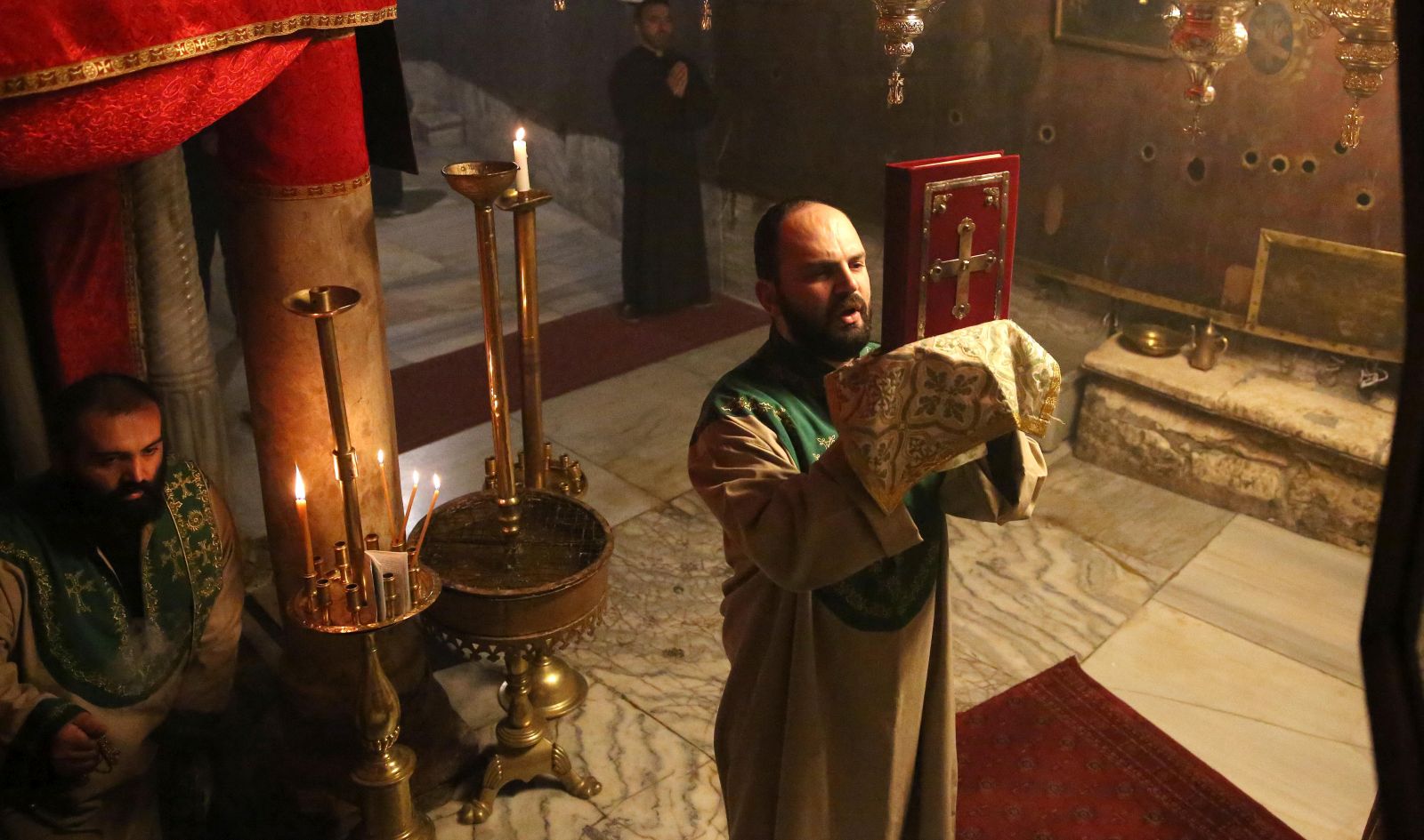 epa08895835 Priests pray during a mass at the Holy Cave in the Church of Nativity in the West Bank town of Bethlehem, 20 December 2020. Palestinian Authorities imposed a total lockdown in West Bank from 20 December – 02 January, due to the increase in COVID-19 cases among Palestinians, with one-day exceptions of the  Bethlehem city to allow the Christmas market.  EPA/ABED AL HASHLAMOUN