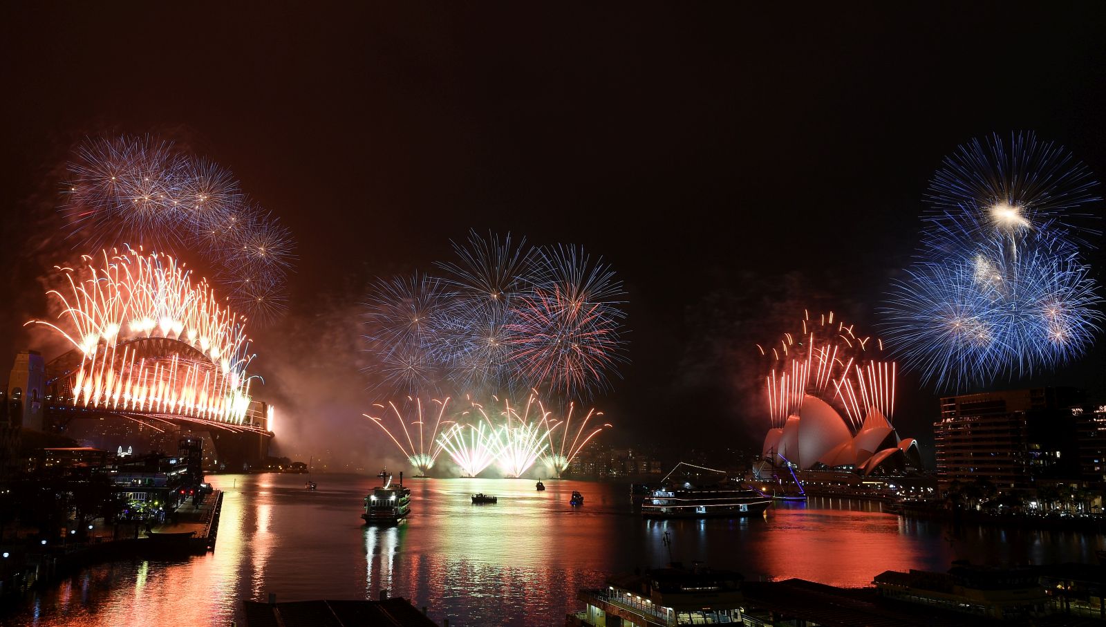 epa08912420 The midnight fireworks light up Sydney Harbour and the Sydney Harbour Bridge during New Year’s Eve celebrations in Sydney, Austrlia, 01 January 2021. Sydneysiders were asked to stay home and watch the fireworks on television this year to due the COVID-19 pandemic.  EPA/DAN HIMBRECHTS  AUSTRALIA AND NEW ZEALAND OUT