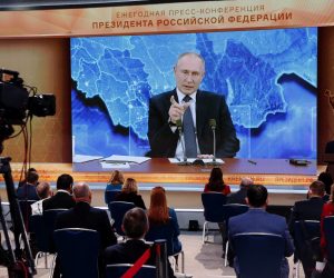 epa08889676 Journalists look at a screen showing Russian President Vladimir Putin speaking during his annual press conference via a video link from the Novo-Ogaryovo state residence, at the World Trade Center in Moscow, Russia, 17 December 2020. Due to Covid-19 pandemic Putin holds his news conference this year in a remote format staying in the Novo-Ogaryovo residence while journalists of federal and foreign media ask their questions via video link from the World Trade Center in Moscow, and regional journalists - from press centers organized in federal districts.  EPA/MAXIM SHIPENKOV