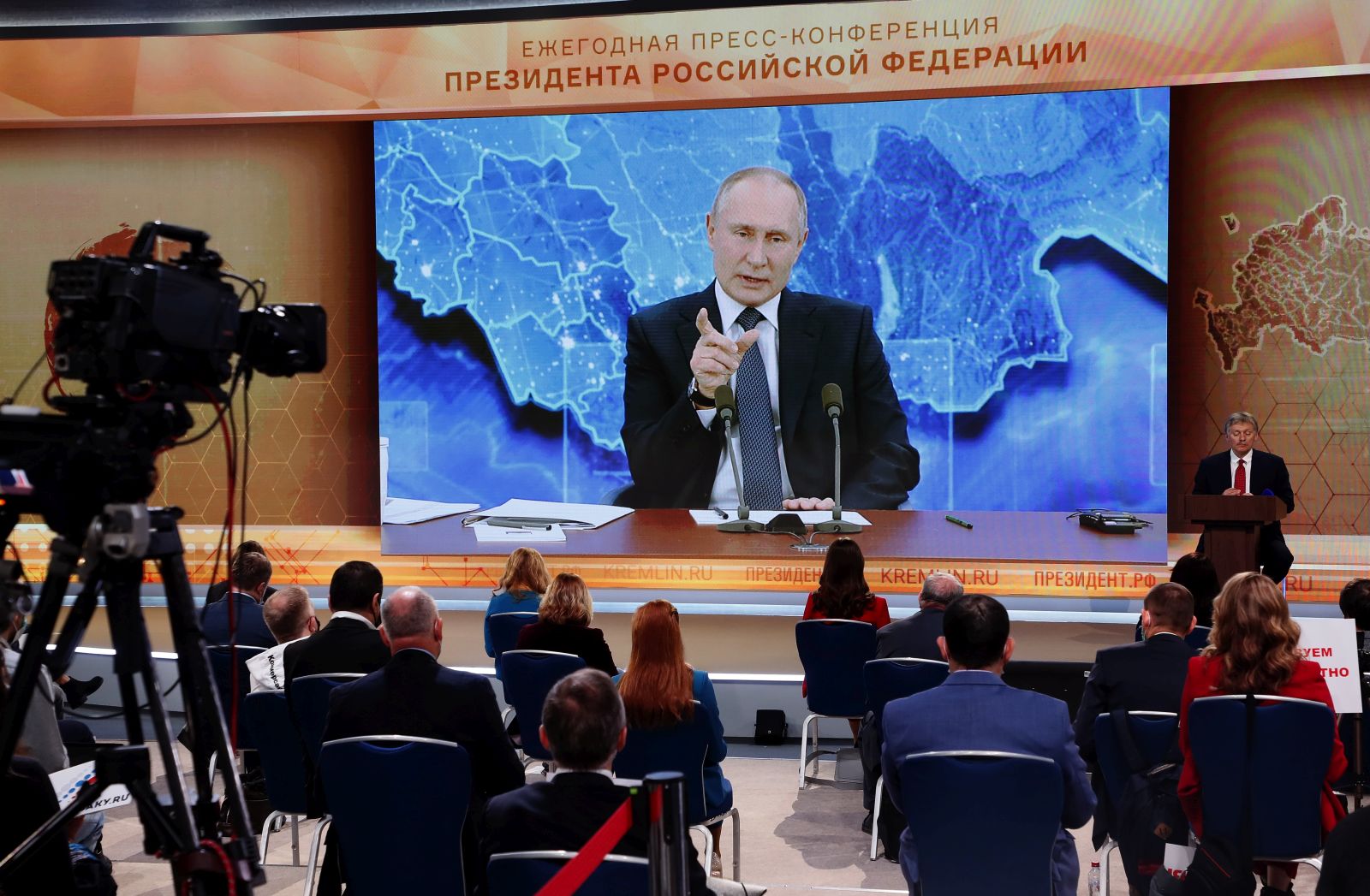 epa08889676 Journalists look at a screen showing Russian President Vladimir Putin speaking during his annual press conference via a video link from the Novo-Ogaryovo state residence, at the World Trade Center in Moscow, Russia, 17 December 2020. Due to Covid-19 pandemic Putin holds his news conference this year in a remote format staying in the Novo-Ogaryovo residence while journalists of federal and foreign media ask their questions via video link from the World Trade Center in Moscow, and regional journalists - from press centers organized in federal districts.  EPA/MAXIM SHIPENKOV