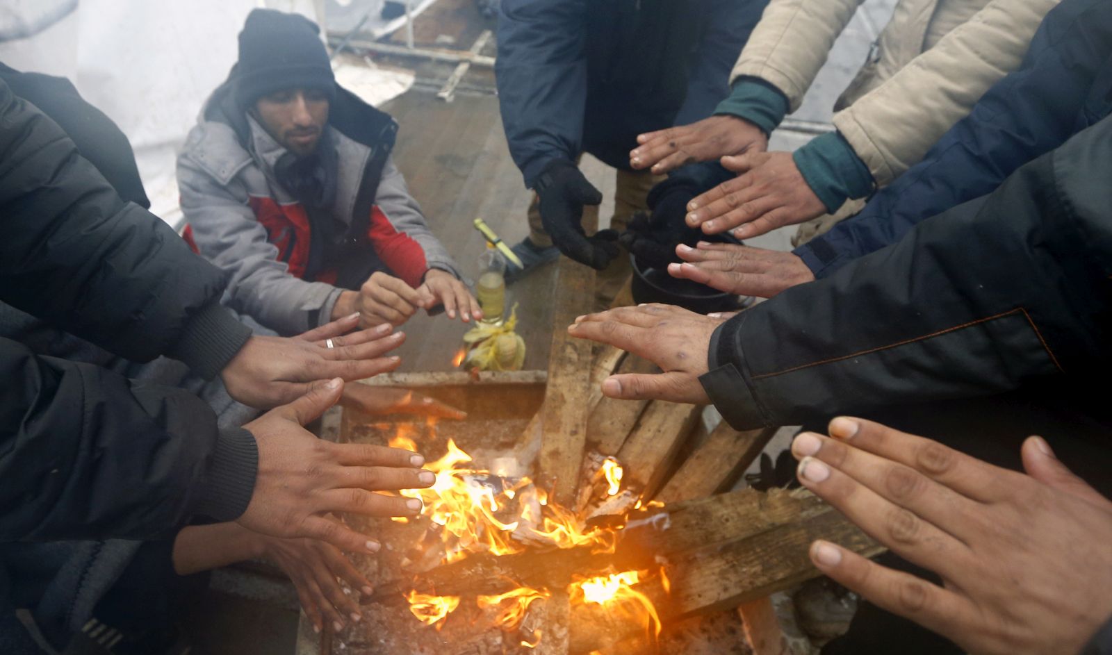 epaselect epa08914523 Migrants warm themselves by a campfire during a winter day at the Lipa refugee camp outside Bihac, Bosnia and Herzegovina, 01 January 2021. Some thousand refugees at the camp were scheduled to be relocated from the burnt-down tent camp on 31 December, yet were returned to Lipa camp. A fire on 23 December destroyed most of the camp near the city of Bihac, which has already been sharply criticized by international authorities and aid groups as unsuitable for accommodating refugees and migrants.  EPA/FEHIM DEMIR