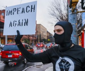 epaselect epa08925402 Micah Wedemeyer holds a sign calling for the impeachment of US President Donald J. Trump, during a small protest in the aftermath of the US Capitol being stormed by Trump's supporters, in Atlanta, Georgia, USA, 07 January 2021.  EPA/ERIK S. LESSER