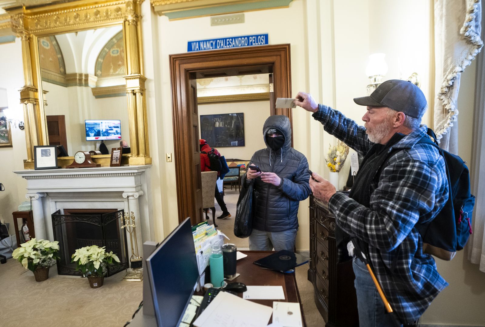 epa08926296 Richard Bigo Barnett (R), a supporter of US President Donald J. Trump and his baseless claims of voter fraud, takes an envelope off a desk in the office of Speaker of the House Nancy Pelosi after breaching Capitol security during a protest against Congress certifying Joe Biden as the next president in Washington, DC, USA, 06 January, 2020 (issued 08 January 2020). On 08 January Assistant House Speaker Katherine Clarke said the House will move to impeach President Trump if the Vice President and Cabinet do not remove him on their own.  EPA/JIM LO SCALZO