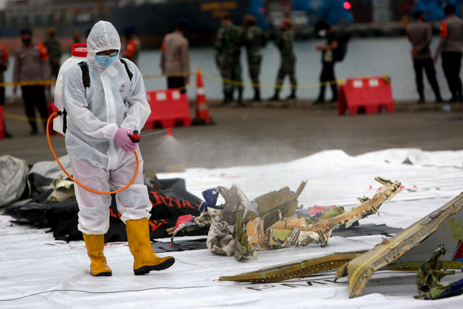 epa08929838 A medical officer sprays desinfectant onto debris of the Sriwijaya Air flight SJ182, found in the water off Jakarta, at Tanjung Priok port in Jakarta, Indonesia, 10 January 2021. Contact to Sriwijaya Air flight SJ182 was lost on 09 January 2021 shortly after the aircraft took off from Jakarta International Airport while en route to Pontianak in West Kalimantan province.  EPA/ADI WEDA