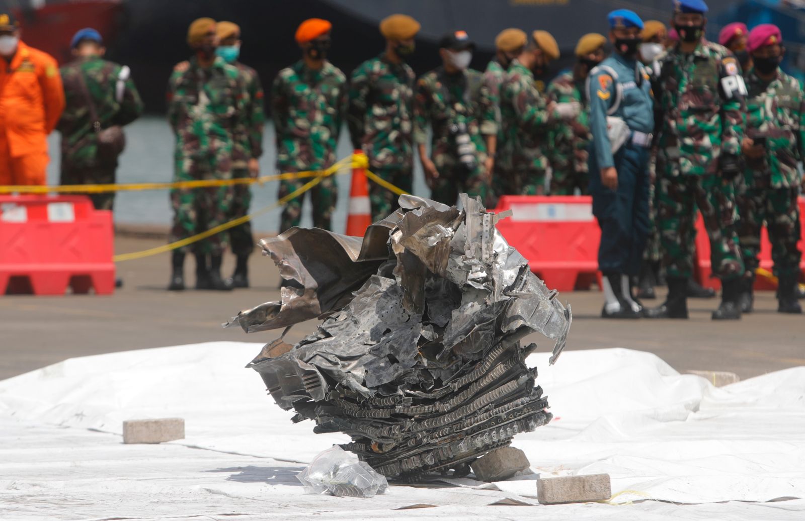 epa08930859 Indonesian soldiers look at a piece of the wrecked engine of Sriwijaya Air flight SJ182, found in the waters off Jakarta, at Tanjung Priok port in Jakarta, Indonesia, 11 January 2021. Sriwijaya Air flight SJ182, with 62 people on board, crashed in to water shortly after take off from Soekarno-Hatta International Airport while en route to Pontianak in West Kalimantan province, on 09 January 2021.  EPA/ADI WEDA