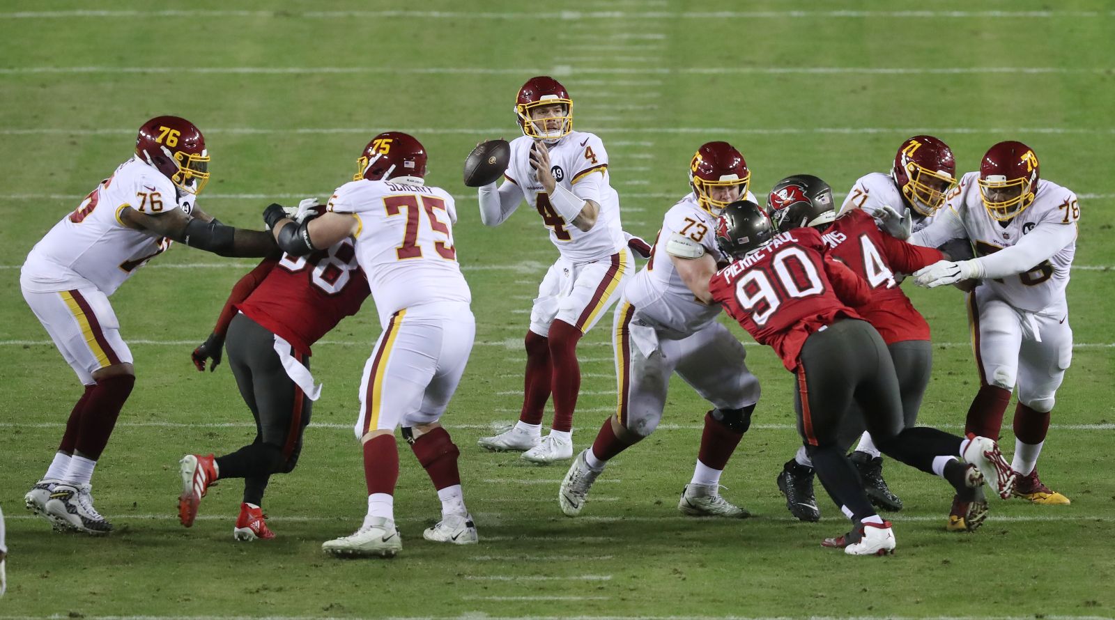 epa08929470 Washington Football Team quarterback Taylor Heinicke (C) drops back to pass against the Tampa Bay Buccaneers during the third quarter of their NFC Wild Card game at FedEx Field in Landover, Maryland, USA, 09 January 2021.  EPA/MICHAEL REYNOLDS