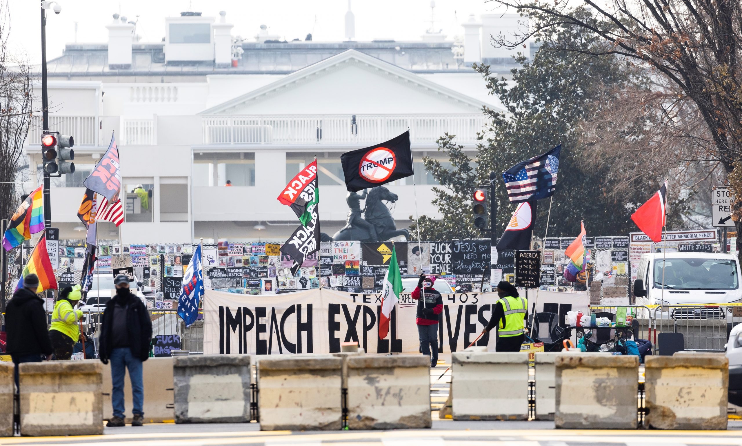 epa08939520 A person with a sign supporting the impeachment of US President Donald J. Trump is seen with the White House in the background in Washington, DC, USA, 15 January 2021. At least twenty thousand troops of the National Guard and other security measures are being deployed in Washington to help secure the Capitol area in response to potentially violent unrest around the inauguration of US President-elect Joe Biden.  EPA/JUSTIN LANE