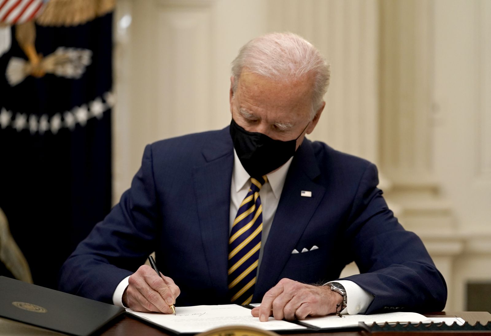 epa08958902 US President Joe Biden signs two executive orders after delivering remarks on his administration's response to the economic crisis in the State Dining Room of the White House in Washington, DC, USA, 22 January 2021.  EPA/Ken Cedeno / POOL