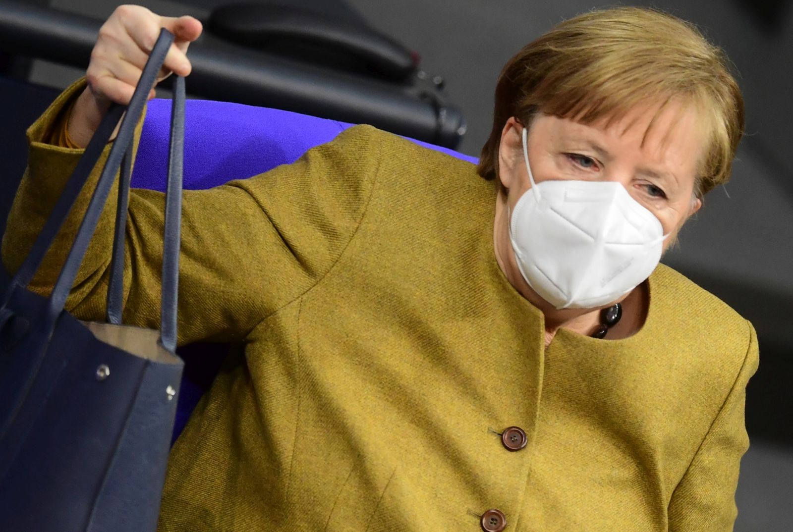epa08970475 German Chancellor Angela Merkel lifts her handbag after a government declaration on the annual economic report 2021 in the German parliament Bundestag in Berlin, Germany, 28 January 2021.  EPA/CLEMENS BILAN