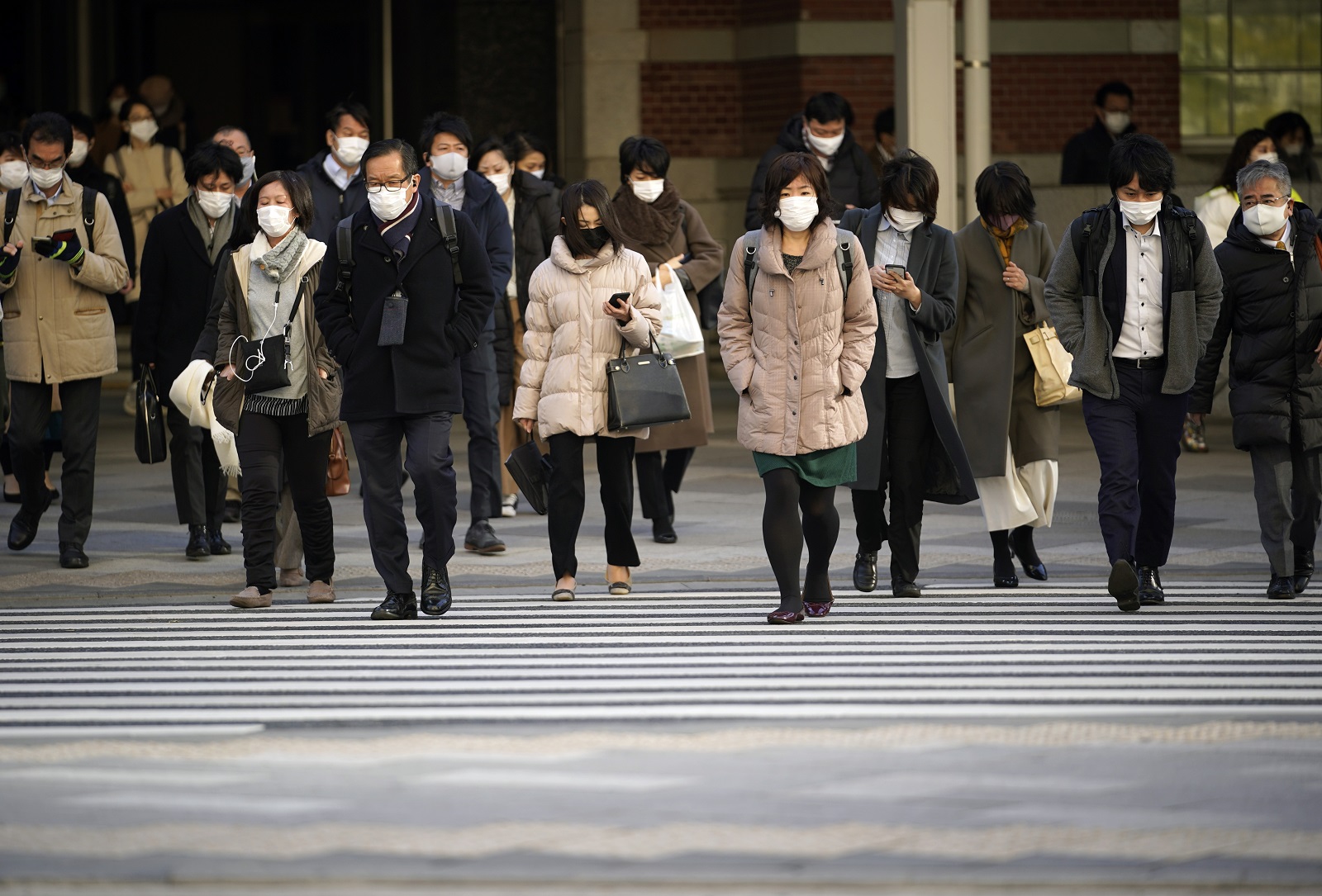 epa08972211 Commuters cross a street at Otemachi business district in Tokyo, Japan, 29 January 2021. According to data released by the Japanese government, the country’s availability ratio marked a decrease of 0.42 points from the previous year to 1.18, its largest decline since 1975, due to the coronavirus pandemic. The annual jobless rate increased slightly to 2.8 percent in 2020.  EPA/FRANCK ROBICHON