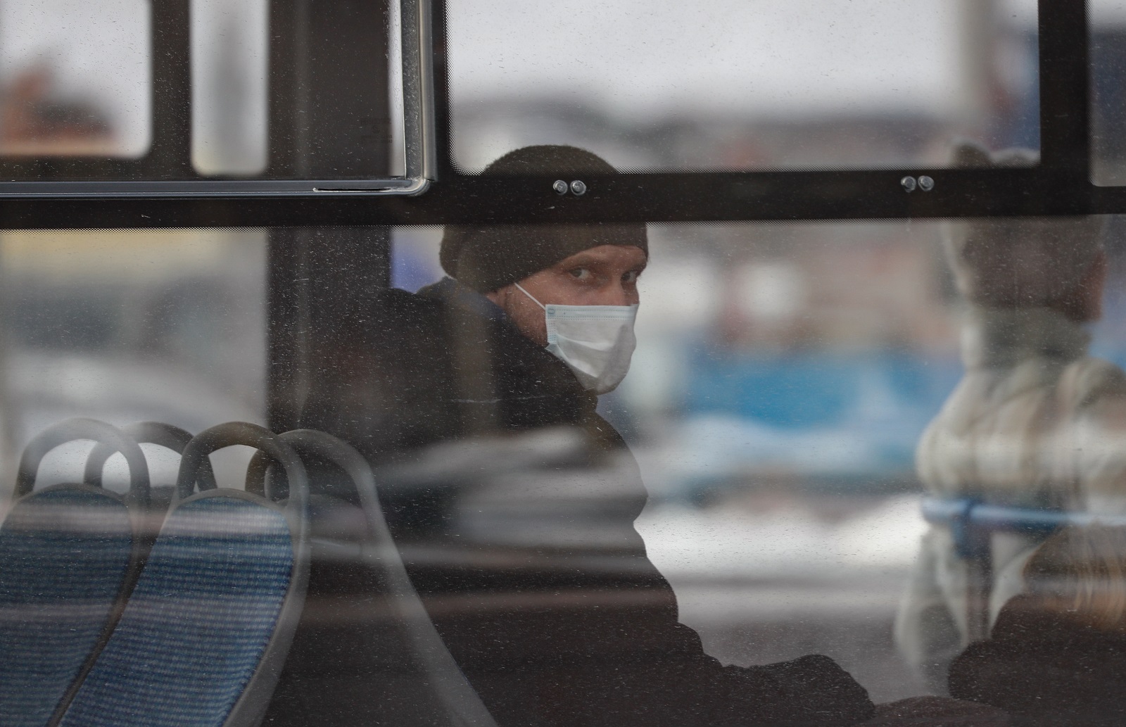 epa08996557 A Russian man wearing a protective face mask sits in a bus in Moscow, Russia, 08 February 2021, during the pandemic of SARS-CoV-2 coronavirus.  EPA/YURI KOCHETKOV