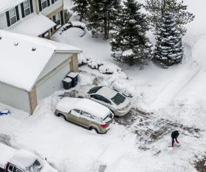 epa09016762 An aerial photo made with a drone shows a man digging out after an overnight snowfall left more than  inches on the ground and roadways in  Illinois, USA, 16 February 2021. Much of the US has been in the grip of winter storms that have sent temperatures plummeting, closed major airports, and caused power outages to millions of people.  EPA/TANNEN MAURY