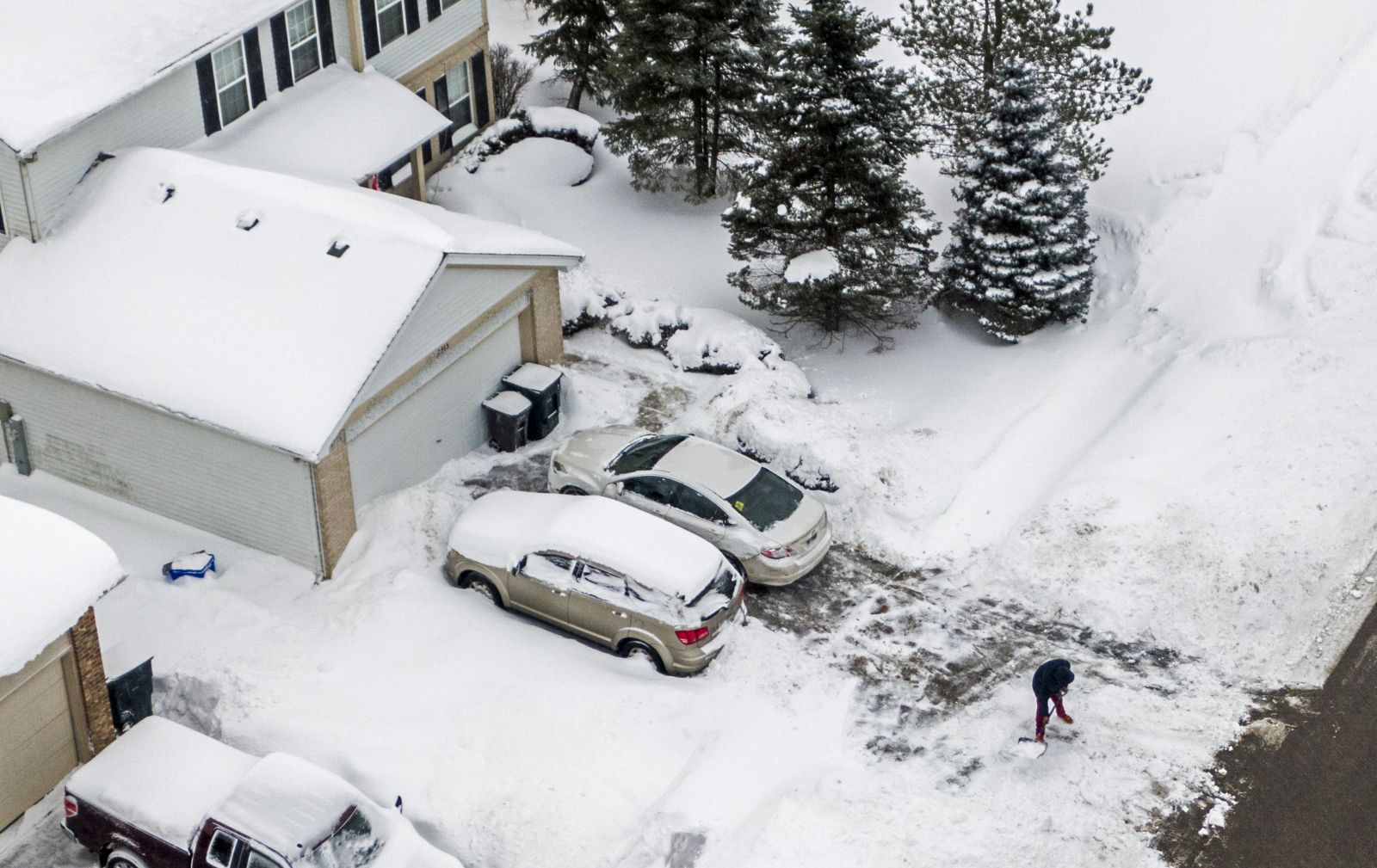 epa09016762 An aerial photo made with a drone shows a man digging out after an overnight snowfall left more than  inches on the ground and roadways in  Illinois, USA, 16 February 2021. Much of the US has been in the grip of winter storms that have sent temperatures plummeting, closed major airports, and caused power outages to millions of people.  EPA/TANNEN MAURY