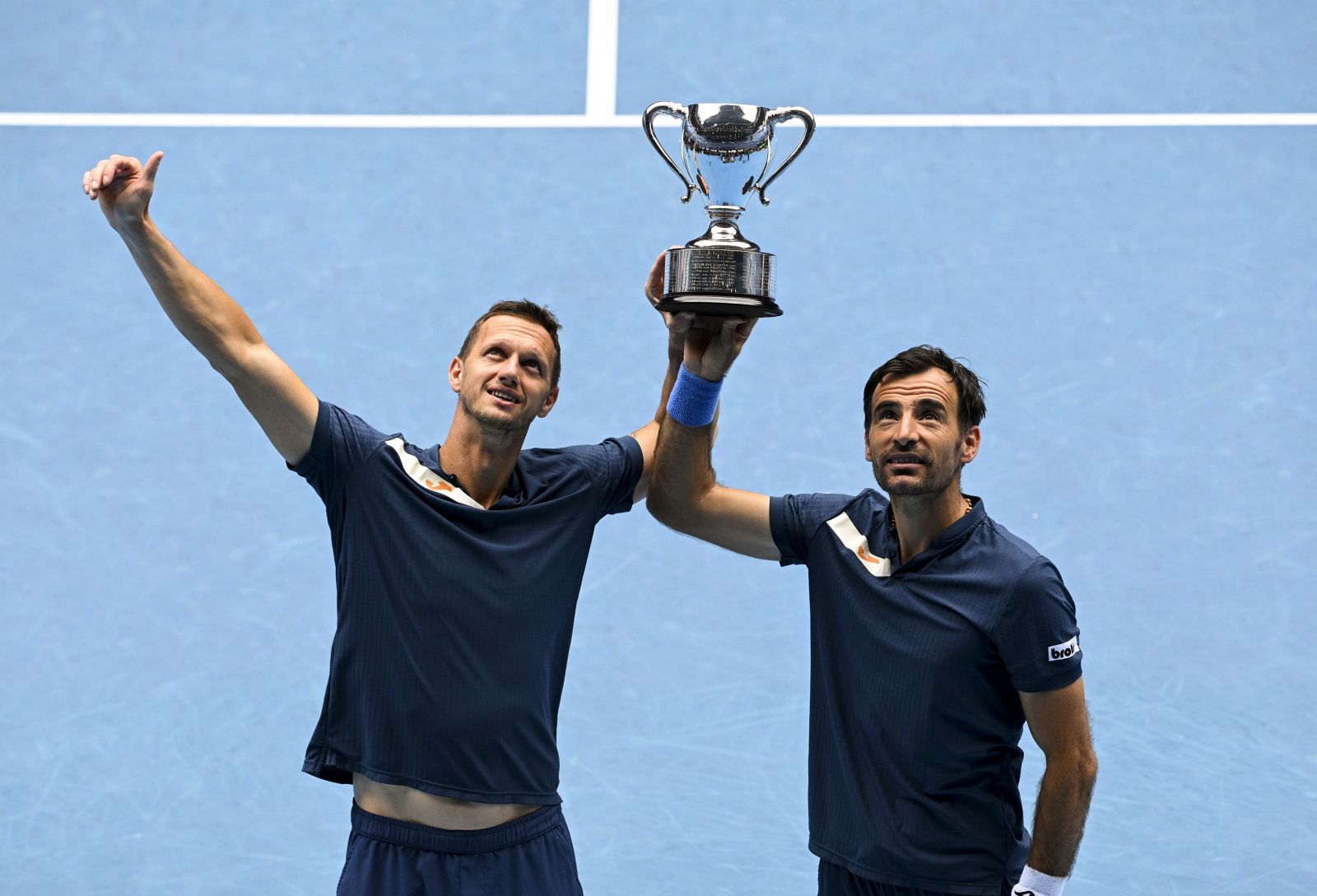 epa09027093 Filip Polasek (L) of Slovakia and Ivan Dodig (R) of Croatia pose for photographs with the winners trophy after winning their men's doubles finals match against Rajeev Ram of the USA and Joe Salisbury of Britain at the Australian Open grand slam tennis tournament at Melbourne Park in Melbourne, Australia, 21 February 2021.  EPA/DEAN LEWINS  AUSTRALIA AND NEW ZEALAND OUT