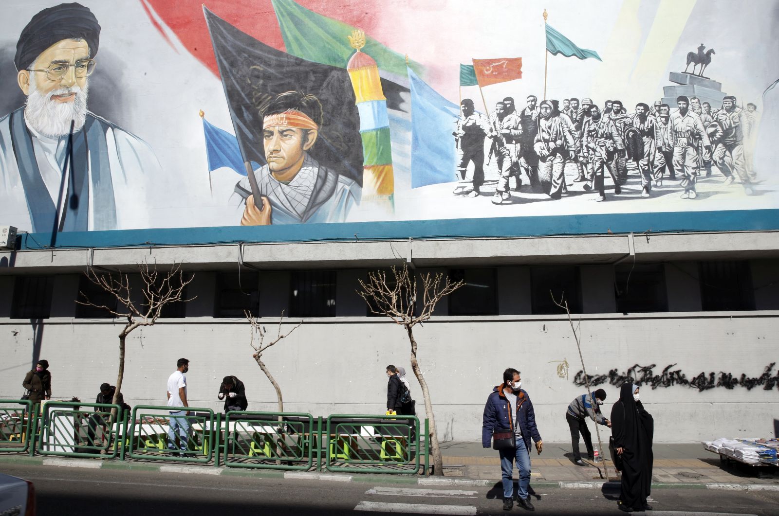 epa09030942 Iranians walk under a wall painting of Iranian supreme leader Ayatollah Ali Khamenei (Top-L) in Tehran, Iran, 23 February 2021. According to the law passed by the Iranian parliament earlier, Iranian government stopped extra inspection from its nuclear facilities by IAEA inspectors as of 23 February 2021 for three months until they reach a new agreement by lifting the US sanctions. IAEA chief Rafael Grossi said a temporary agreement was reached with Iranian government to allow a degree of monitoring until resolving disagreements and restore the 2015 nuclear deal. Iranian supreme leader Ayatollah Khamenei said that if Iran would need to enrich uranium even to 60 percent, the country would do it for its energy system and everything in need, not for building nuclear bombs which would be against one's beliefs and Islam.  EPA/ABEDIN TAHERKENAREH