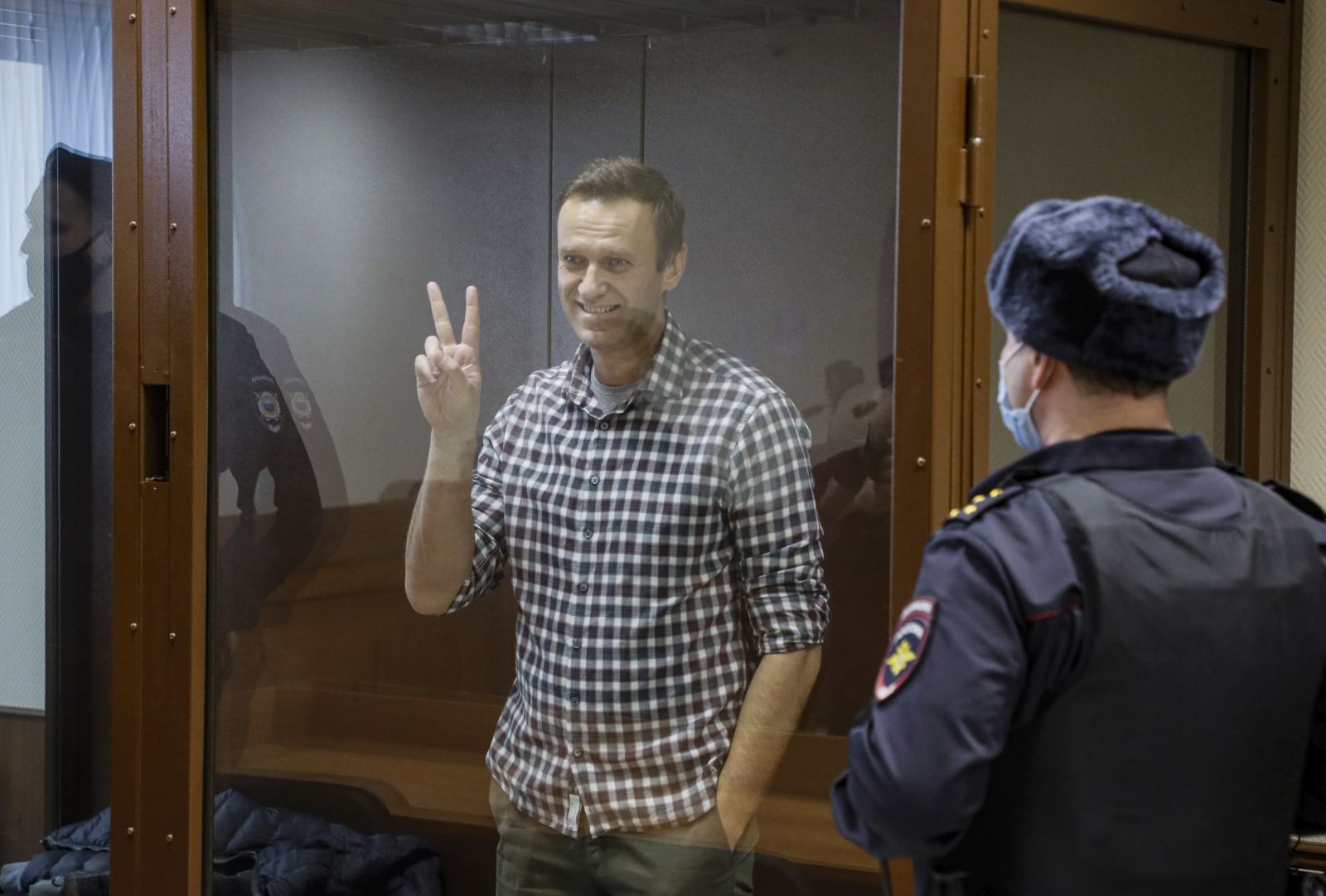 epaselect epa09025242 Russian opposition leader Alexei Navalny gestures inside a glass cage prior to a hearing at the Babushkinsky District Court in Moscow, Russia, 20 February 2021. The Moscow City court will hold a visiting session at the Babushkinsky District Court Building to consider Navalny's lawyers appeal against a court verdict issued on 02 February 2021, to replace the suspended sentence issued to Navalny in the Yves Rocher embezzlement case with an actual term in a penal colony.  EPA/YURI KOCHETKOV MANDATORY CREDIT