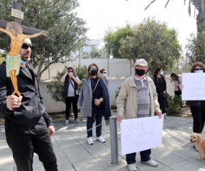 epa09056234 Cypriot demonstrators hold a cross and placards at the entrance of the Cyprus Broadcasting Corporation headquarters in Nicosia, Cyprus, 06 March 2021. Orthodox people of Cyprus protest against the choice of this year's Eurovision song titled 'El Diablo' to represent the country by Greek singer Elena Tsagrinou claiming that the song is promoting the devil.  EPA/KATIA CHRISTODOULOU