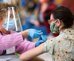 epa09070826 Registered nurse Angela Biccolo (L) administers a dose of the Moderna Covid-19 vaccine to a Revere school teacher (R) during a vaccine clinic for teachers and school administrators at the Rumney March Academy, in Revere, Massachusetts, USA, 12 March 2021. Massachusetts Governor Charlie Baker set aside four days for school personnel to be vaccinated after earlier being criticized for wanting schools to resume in person learning before all teachers were vaccinated.  EPA/CJ GUNTHER