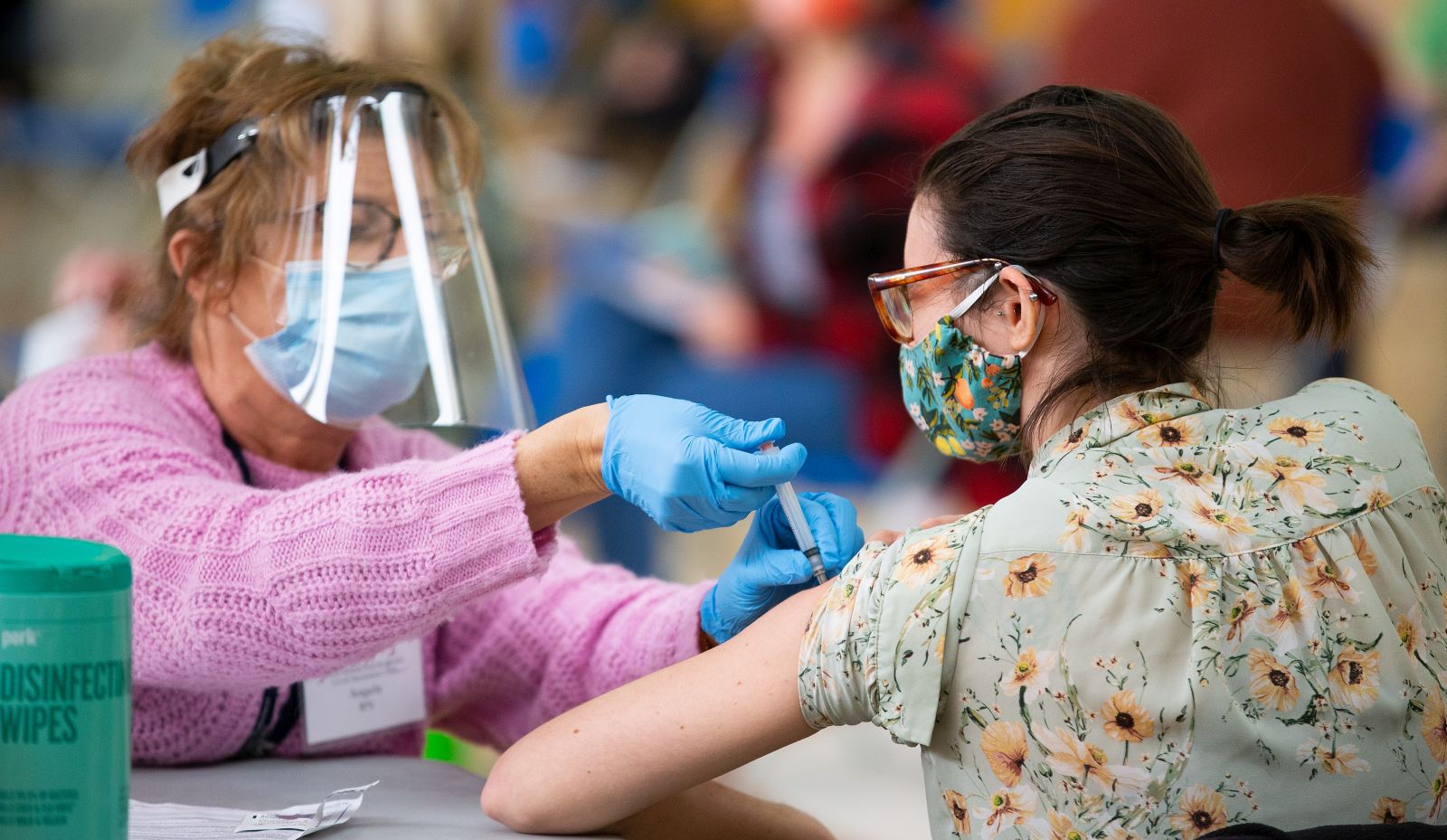 epa09070826 Registered nurse Angela Biccolo (L) administers a dose of the Moderna Covid-19 vaccine to a Revere school teacher (R) during a vaccine clinic for teachers and school administrators at the Rumney March Academy, in Revere, Massachusetts, USA, 12 March 2021. Massachusetts Governor Charlie Baker set aside four days for school personnel to be vaccinated after earlier being criticized for wanting schools to resume in person learning before all teachers were vaccinated.  EPA/CJ GUNTHER