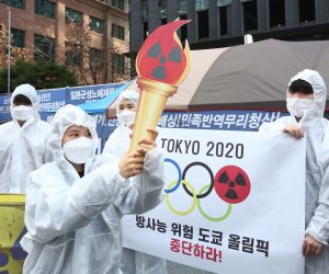 epa09095301 Members of an environmental group wearing mock hazmat suits perform during a protest against Tokyo Olympics near the Japanese embassy in Seoul, South Korea, 25 March 2021. The Summer Olympics in Tokyo is scheduled to start on 23 July and the torch relay event began on 25 March from nuclear disaster-hit Fukushima in Japan.  EPA/JEON HEON-KYUN