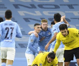 epa09119259 Kevin De Bruyne (back-C) of Manchester City celebrates with teammates after scoring the 1-0 lead as Emre Can (front, bottom) of Dortmund reacts during the UEFA Champions League quarterfinal, 1st leg soccer match between Manchester City and Borussia Dortmund in Manchester, Britain, 06 April 2021.  EPA/PETER POWELL