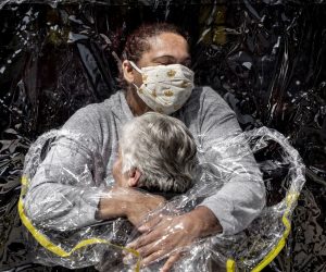 epa09137088 A handout photo made available by World Press Photo (WPP) organization shows a picture by Mads Nissen, winner of the General News - First Prize Singles category in the World Press Photo 2021 Contest as it was announced by World Press Photo on 15 April 2021. 

Rosa Luzia Lunardi (85) is embraced by nurse Adriana Silva da Costa Souza, at Viva Bem care home, São Paulo, Brazil, on 5 August.  

Story: 
This was the first hug Rosa had received in five months. In March, care homes across the country had closed their doors to all visitors as a result of the COVID-19 pandemic, preventing millions of Brazilians from visiting their elderly relatives. Carers were ordered to keep physical contact with the vulnerable to an absolute minimum. At Viva Bem, a simple invention, ‘The Hug Curtain', allowed people to hug each other once again. The new coronavirus had first appeared in Wuhan, China, at the end of 2019, and by January 2020 had begun to spread around the world. On 11 March, the World Health Organisation declared the COVID-19 outbreak a pandemic. The disease—transmitted mainly via close contact, respiratory droplets, and aerosols—could be fatal, and people over the age of 70 were one of the groups considered most vulnerable to the disease. Brazilian president, Jair Bolsonaro, dismissed claims about the severity of the pandemic and the danger posed by the virus, undermined quarantine measures adopted at state level, and encouraged Brazilians to continue working to keep the economy afloat. Brazil ended 2020 with one of the worst records globally in dealing with the virus, with some 7.7 million reported cases and 195,000 deaths.  EPA/Mads Nissen/ Politiken/ Panos Pictures / WPP /  HANDOUT NO CROPPING / NO MANIPULATING / USE ONLY FOR SINGLE PUBLICATION IN CONNECTION WITH THE WORLD PRESS PHOTO AND ITS ACTIVITIES HANDOUT EDITORIAL USE ONLY/NO SALES
