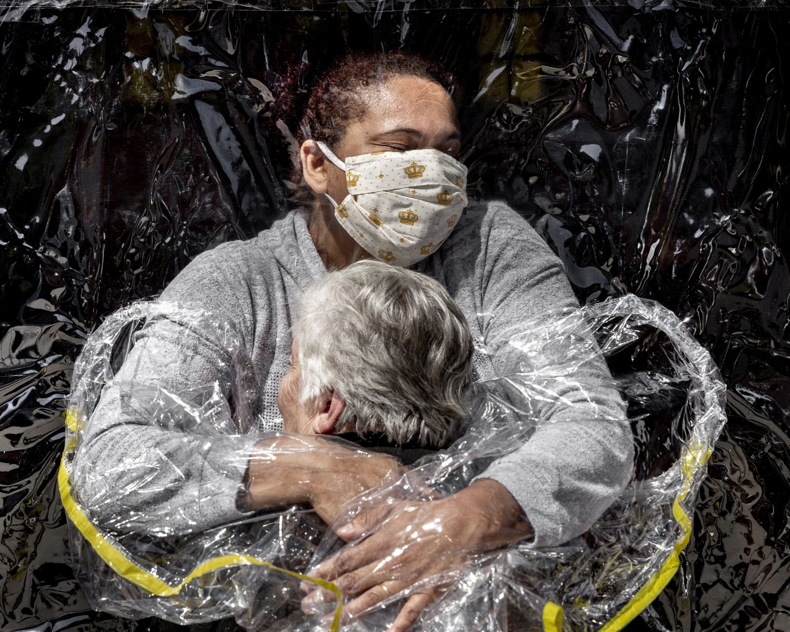 epa09137088 A handout photo made available by World Press Photo (WPP) organization shows a picture by Mads Nissen, winner of the General News - First Prize Singles category in the World Press Photo 2021 Contest as it was announced by World Press Photo on 15 April 2021. 

Rosa Luzia Lunardi (85) is embraced by nurse Adriana Silva da Costa Souza, at Viva Bem care home, São Paulo, Brazil, on 5 August.  

Story: 
This was the first hug Rosa had received in five months. In March, care homes across the country had closed their doors to all visitors as a result of the COVID-19 pandemic, preventing millions of Brazilians from visiting their elderly relatives. Carers were ordered to keep physical contact with the vulnerable to an absolute minimum. At Viva Bem, a simple invention, ‘The Hug Curtain', allowed people to hug each other once again. The new coronavirus had first appeared in Wuhan, China, at the end of 2019, and by January 2020 had begun to spread around the world. On 11 March, the World Health Organisation declared the COVID-19 outbreak a pandemic. The disease—transmitted mainly via close contact, respiratory droplets, and aerosols—could be fatal, and people over the age of 70 were one of the groups considered most vulnerable to the disease. Brazilian president, Jair Bolsonaro, dismissed claims about the severity of the pandemic and the danger posed by the virus, undermined quarantine measures adopted at state level, and encouraged Brazilians to continue working to keep the economy afloat. Brazil ended 2020 with one of the worst records globally in dealing with the virus, with some 7.7 million reported cases and 195,000 deaths.  EPA/Mads Nissen/ Politiken/ Panos Pictures / WPP /  HANDOUT NO CROPPING / NO MANIPULATING / USE ONLY FOR SINGLE PUBLICATION IN CONNECTION WITH THE WORLD PRESS PHOTO AND ITS ACTIVITIES HANDOUT EDITORIAL USE ONLY/NO SALES