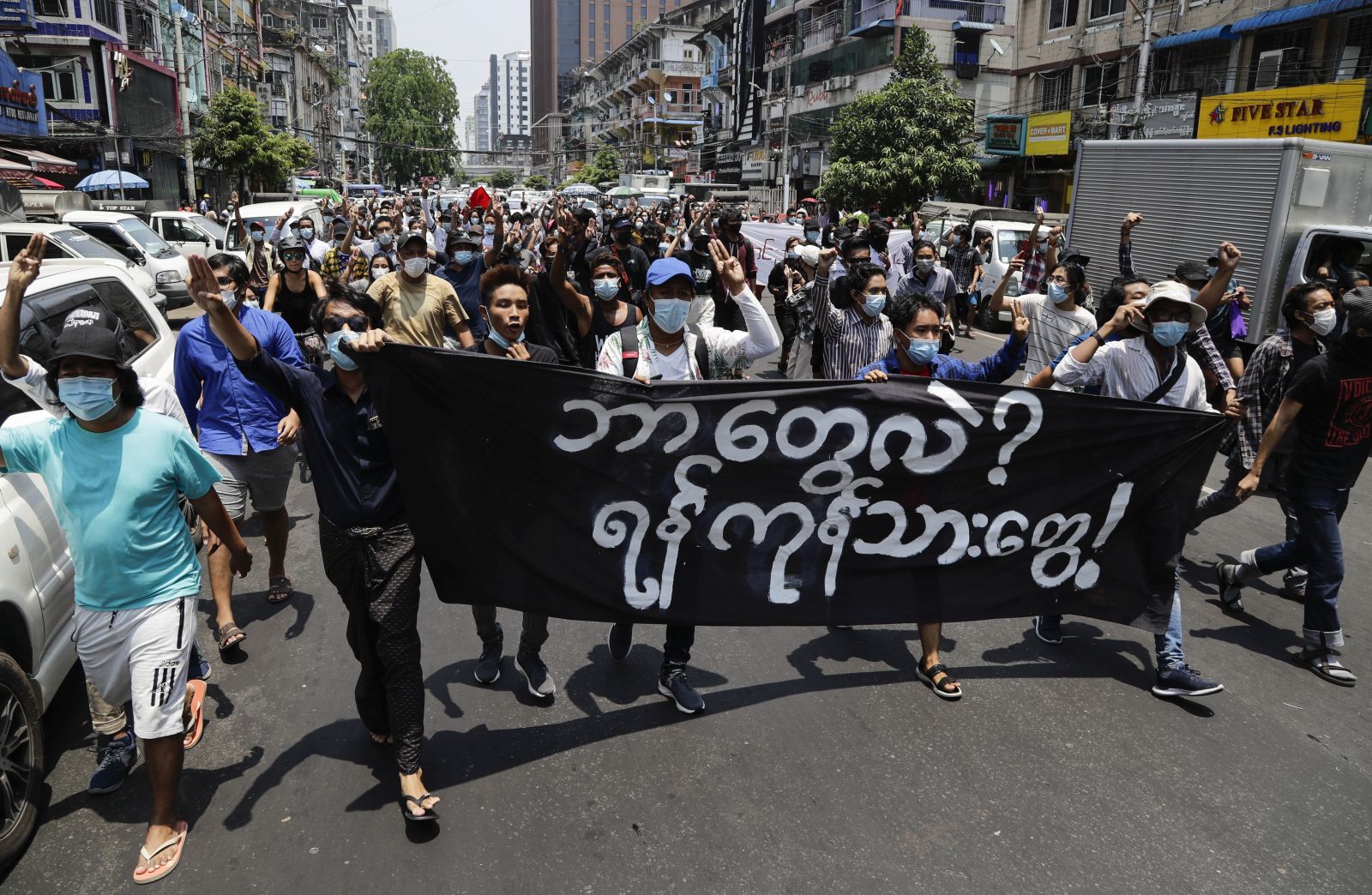epa09154147 Demonstrators hold a banner that reads 'What is this? We are Yangon people', as they march during a protest against the military coup in downtown Yangon, Myanmar, 23 April 2021. According to the United Nations, nearly 3.5 million people in Myanmar may struggle to afford food in the coming months in the wake of the military coup and financial crisis.  EPA/STRINGER