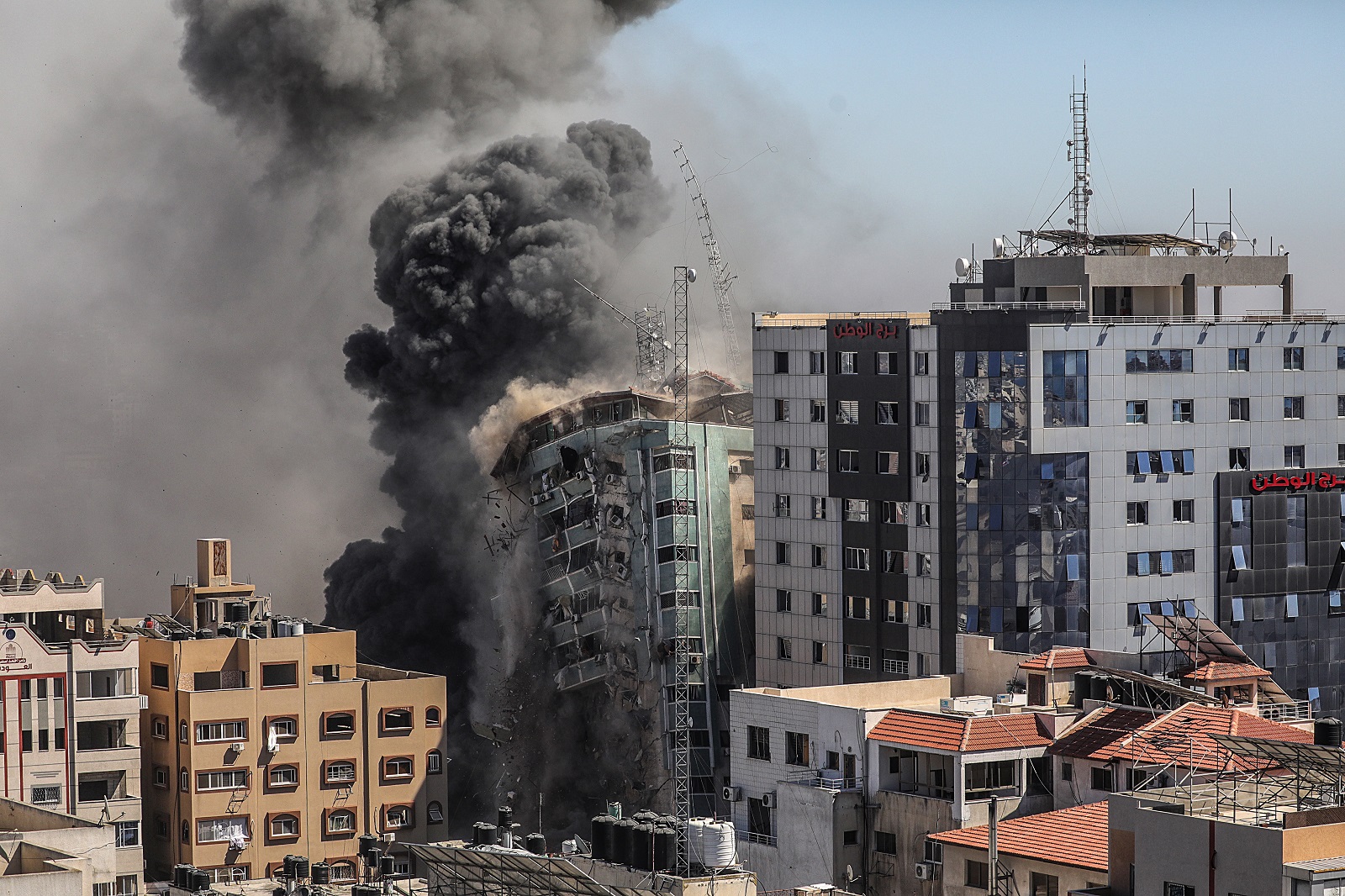 epa09201794 Smoke rises as the building collapses after an Israeli airstrike hits Al-Jalaa tower, which houses apartments and several media outlets, including The Associated Press and Al Jazeera, in Gaza City, 15 May 2021. In response to days of violent confrontations between Israeli security forces and Palestinians in Jerusalem, various Palestinian militants factions in Gaza launched rocket attacks since 10 May that killed at least nine Israelis to date. According to the Palestinian Ministry of Health, at least 139 Palestinians, including 39 children, were killed in the recent retaliatory Israeli airstrikes.  EPA/MOHAMMED SABER