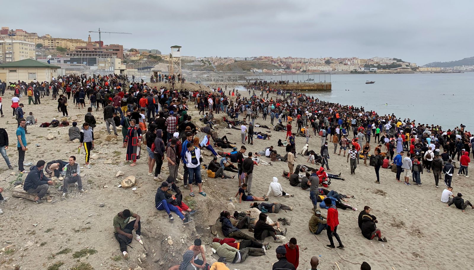 epa09208248 Hundreds of people wait at the border in Fnideq, Morocco, in an attempt to cross to Ceuta, Spanish enclave at the border with Morocco, in Fnideq, Morocco, 18 May 2021. Spanish army troops are deployed after about 5,000 Moroccan nationals managed to entry the Ceuta city by sea during the night and hundreds continue to arrive.  EPA/MOHAMED SIALI