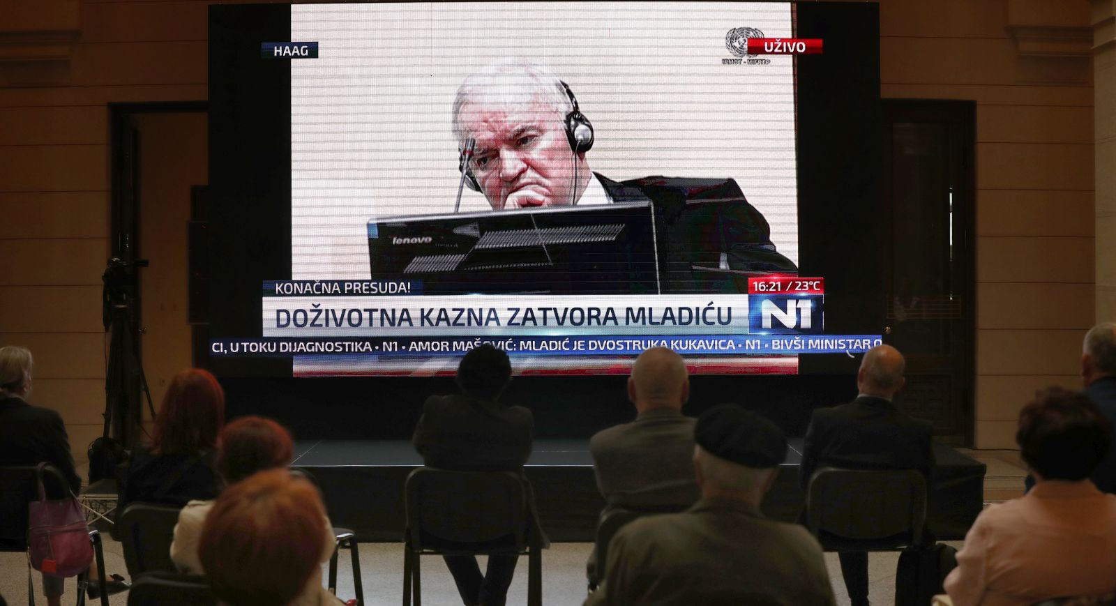epa09255515 People watch the transmission of the International Criminal Tribunal for Former Yugoslavia court appeals verdict session for war-time Bosnian Serb, General Ratko Mladic during his trial in The Hague, broadcasted on TV in Sarajevo, Bosnia, 08 June 2021. Ratko Mladic, was sentenced to life imprisonment by the ICY on 08 June, after the judges found him guilty of the 1995 Srebrenica Genocide in which 8,000 Muslim men and boys were killed and other war crimes charges.  EPA/FEHIM DEMIR